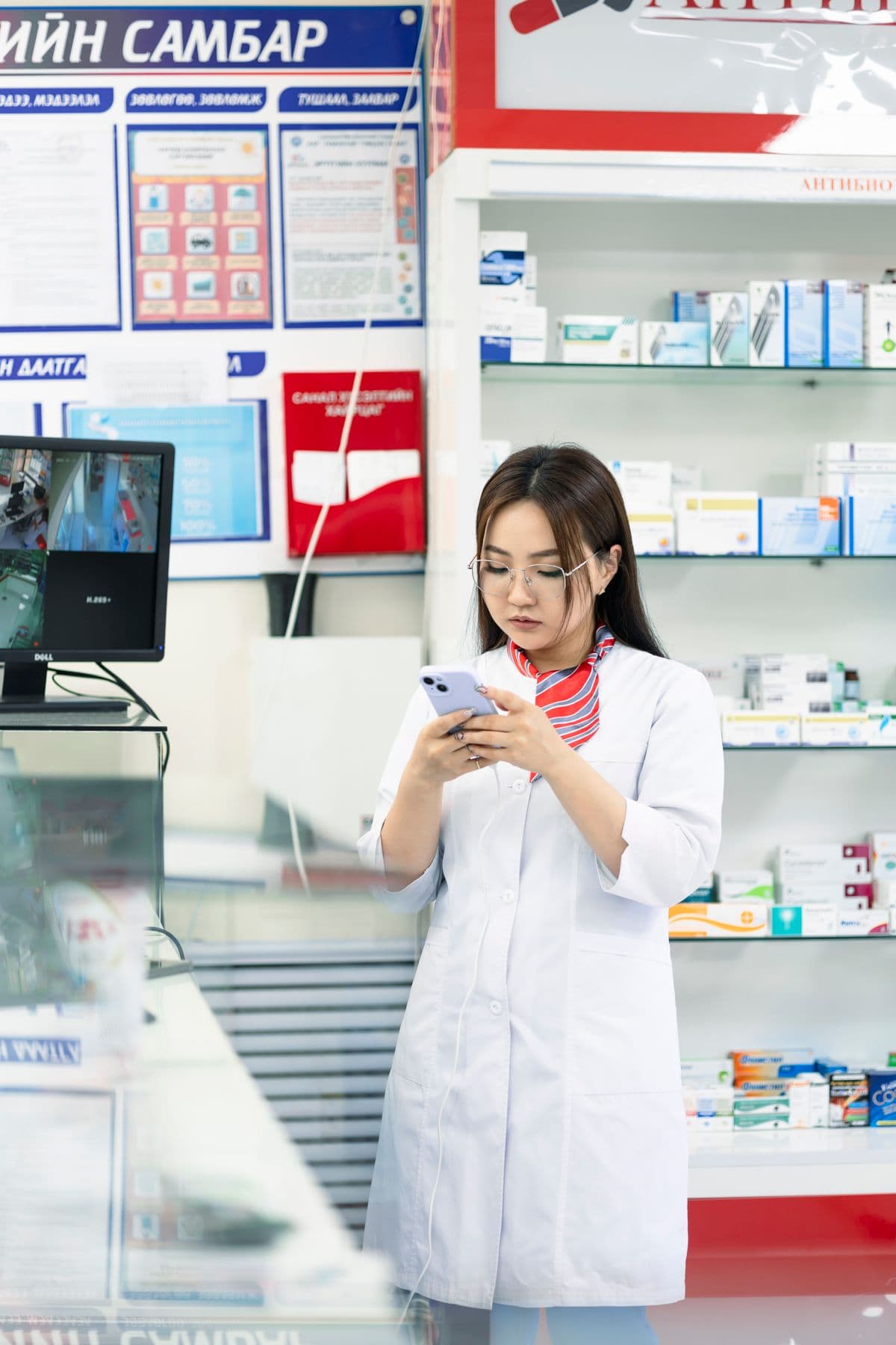 Apothekerin mit Smartphone in der Apotheke